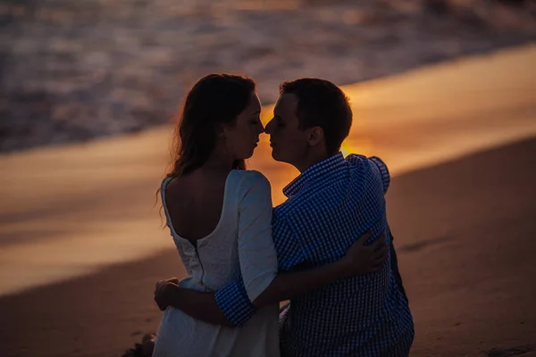 Dois jovens amantes de pé em uma praia e olhando um para o outro no pôr do sol background.sillhouette casal amor — Fotografia de Stock