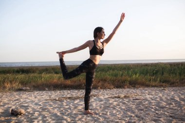 İnce yapılı esmer genç kadın pratik Yoga, kum plaj. Uzay kopyalayın. Sağlıklı stil spor. virabhadrasana