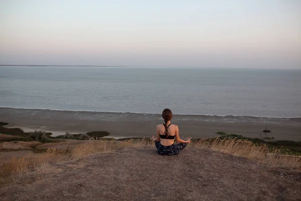 Irriconoscibile giovane donna Praticare Yoga in Lotus posa seduto sul bordo della roccia contro di vedere. Padmasana — Foto Stock