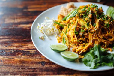 Padthai noodle duman tofu ve karışık sebze - buğday mikroplar, limon, salatalık, maydanoz ahşap dokulu tablo ile kapatın. Sağlıklı vegan Vejetaryen Menü