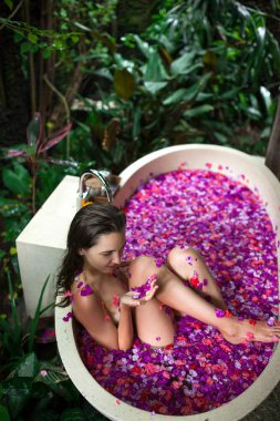 Güzellik genç kadın tropikal çiçek ile açık banyosunda rahatlatıcı