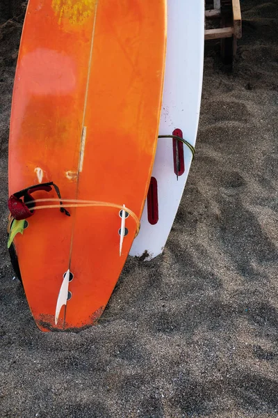 Dos tablas de surf de color que yacen en la playa de arena por el océano . — Foto de Stock