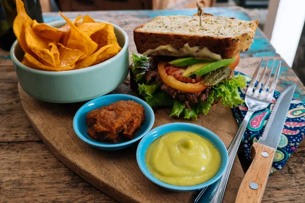 Hälsosam snabbmat. hamburgare med en kotlett, sallad med sötpotatis frites och två såser. Välsmakande smörgås till lunch på träbord i Café. begreppet hälsokost — Stockfoto