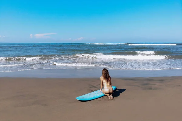 Visão traseira da bunda sexy da bela mulher de surf esportivo em biquíni sexy sentar perto de prancha de surf longboard prancha na praia antes de surfar. Estilo de vida esportivo ativo moderno e férias de verão — Fotografia de Stock