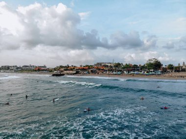 Canggu, Bali, Endonezya - 15 Şubat 2019: Bali'nin batısında, güzel gökyüzüile gün batımında bulunan Canggu plajında sörf tahtasında dalga yakalayan adamın havadan görünümü