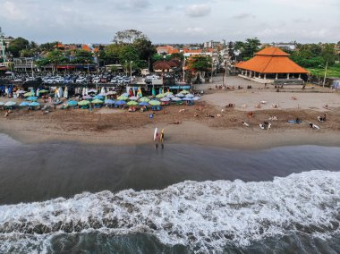 Canggu, Bali, Endonezya - 15 Şubat 2019: Bali'nin batısında bulunan sörfçüler ve şemsiyelerle Canggu plajının havadan görünümü