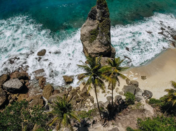 Tropikal plaj, deniz kayaları, turkuaz okyanus ve palmiye ağaçlarının havadan drone fotoğraf. Atuh plajı, Nusa Penida adası, Bali, Endonezya. Tropikal arka plan ve seyahat konsepti