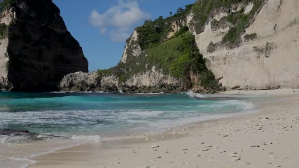 Baksidan bild av kvinnan i svart baddräkt promenader längs havet stranden med stenar och turkos hav, blå himmel. Stranden Atuh, ön Nusa Penida, Bali, Indonesien. Tropiskt resekoncept. — Stockvideo