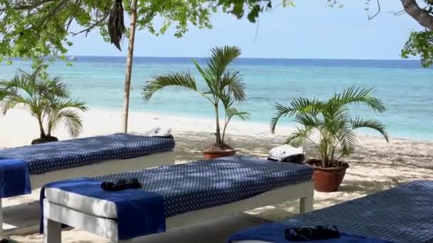 Massagetafels tussen palmbomen, vlakbij de zee op strand met wit zand op een exotische locatie op Gili Island, Indonesië. Niemand.. — Stockvideo