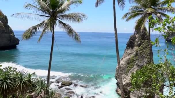 Nő piros ruhában swing a trópusi Diamond Beach, Nusa Penida. Kilátás drón tengeri sziklák, türkiz óceán Bali Indonézia — Stock videók