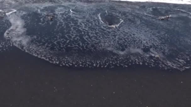 Primer plano de vídeo de olas con espuma rodando hasta la playa de arena volcánica negro océano, Bali, Indonesia — Vídeos de Stock