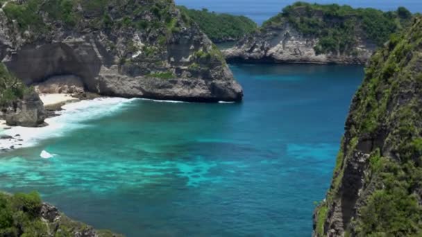 Flygdrönare zoomning utsikt över tropiska stranden, hav stenar, turkos hav och palmer. Stranden Atuh, ön Nusa Penida, Bali, Indonesien. Populära resmål och turistmål — Stockvideo