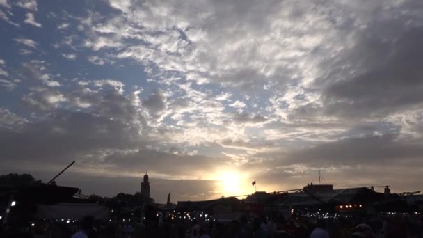 Marokkó, Marrakech - Október 2019: Lenyűgöző narancssárga naplemente ég felett a Marrakesh medina város fő Jemaa el-Fnaa tér sziluettek az emberek — Stock videók