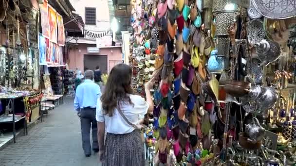 Marokko, Marrakech - oktober 2019: Vrouw kiest voor handgemaakte traditionele leaver schoenen in Medina Marrakech markt, Arabische traditionele toeristische vakantie concept — Stockvideo