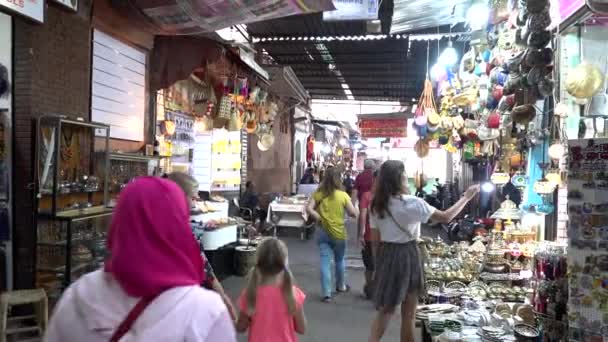 Marrocos, Marraquexe - Outubro 2019: beco na Medina com vendedores do mercado local e turistas caminhando. Mulher escolhendo lembranças tradicionais e decoração de lanterna de prata — Vídeo de Stock