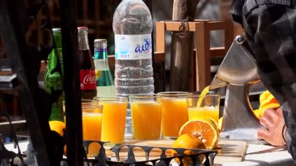 Marokko, Todra - oktober 2019: Marokkaan knijpt sinaasappelsap met handmatige sappers en maakt een vol glas vers sinaasappelsap op een Marokkaanse straatkraam — Stockvideo