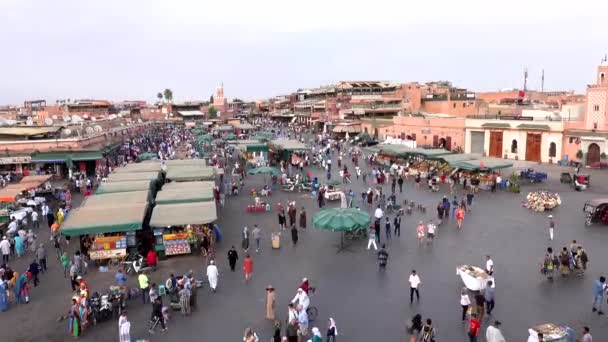 Maroko, Marrakesz - październik 2019: Widok placu Jemaa el-Fna o zmierzchu z przemieszczającymi się ludźmi między rzędami stoiska na rynku od góry w czasie zachodu słońca — Wideo stockowe
