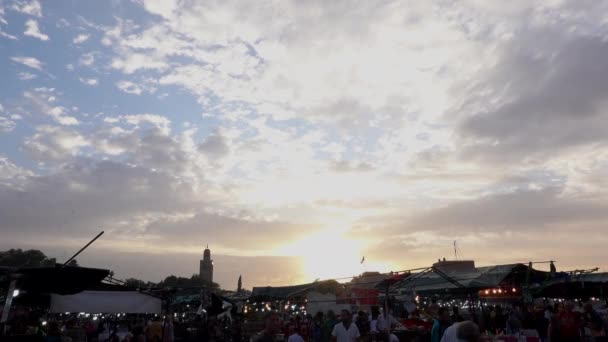 Marokko, Marrakesch - Oktober 2019: Atemberaubender Sonnenuntergang mit Wolken über der Medina-Stadt Marrakesch vom Hauptplatz Jemaa el-Fnaa mit Menschensilhouetten — Stockvideo