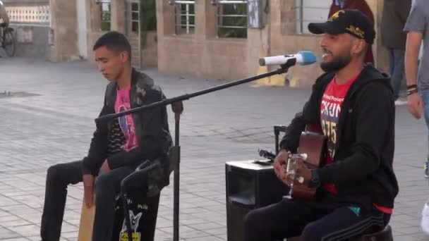 Marocko, Essaouira - oktober 2019: Närbild på två arabiska män som spelar gitarr och traditionell trumma under en liveföreställning utanför. Gatuartister — Stockvideo