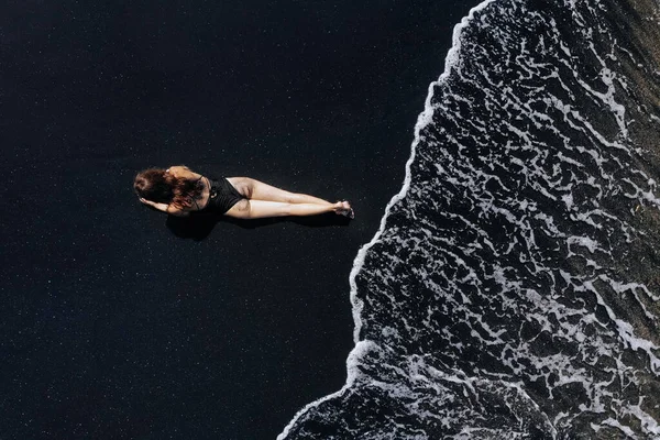 Aerial View Girl Black Swimsuit Lying Beach Black Sand Foaming — Stock Photo, Image