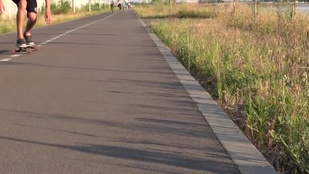 Face close view van de mens rijdt longboard zitten op lege rechte weg. Zomer vakantie hipster rijdt skateboard buiten de stad bij zonsondergang tijd. Hoge kwaliteit 4k beeldmateriaal — Stockvideo