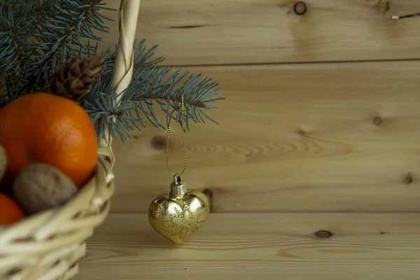Sıcak bir ahşap arka plan üzerinde portakal, elma, Noel ağacı ve Noel oyuncakları ile bir sepet içinde Noel kompozisyon, tatil kavramı