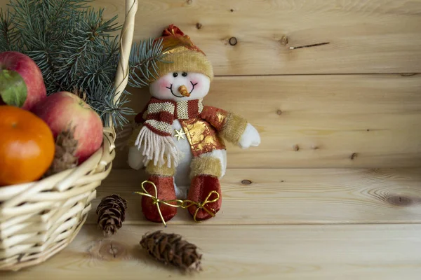 Sıcak bir ahşap arka plan üzerinde portakal, elma, Noel ağacı ve kardan adam ile bir sepet içinde Noel kompozisyon