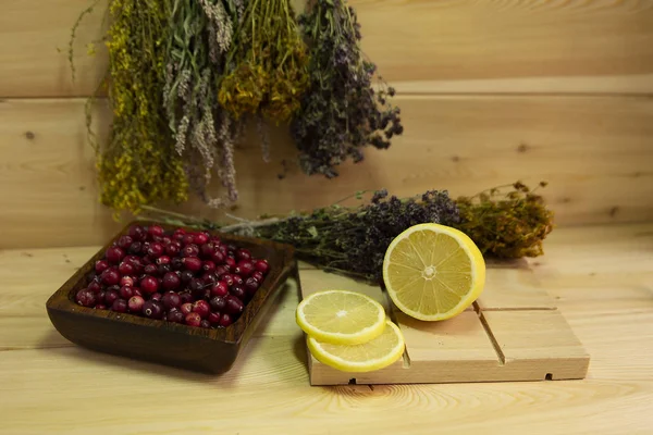 Kırmızı yaban mersini, ahşap kase, sarı limon, şifalı bitki. Ahşap arka plan. Sağlık kavramı. Gribi önleme