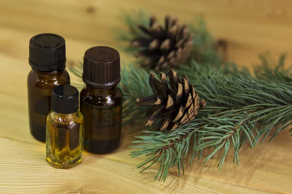 Cam şişelerde ladin yağı. Bir konisiyle Noel ağacı. Ahşap arka plan. Alternatif tedavi. Sağlık