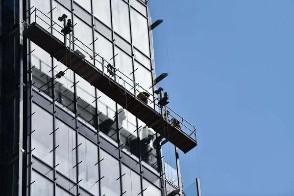 Lavoratori Edili Una Piattaforma Sospesa Una Facciata Vetro Grattacielo — Foto Stock