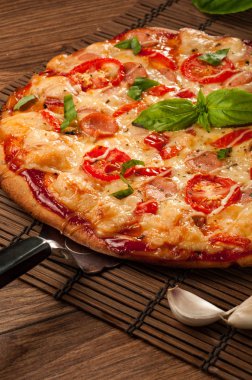 Sıcak pizza dilimi, erimiş peynirle ahşap bir masada.