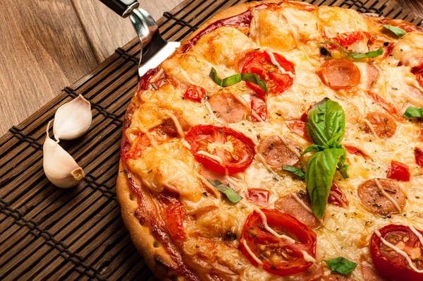 Sıcak pizza dilimi, erimiş peynirle ahşap bir masada.