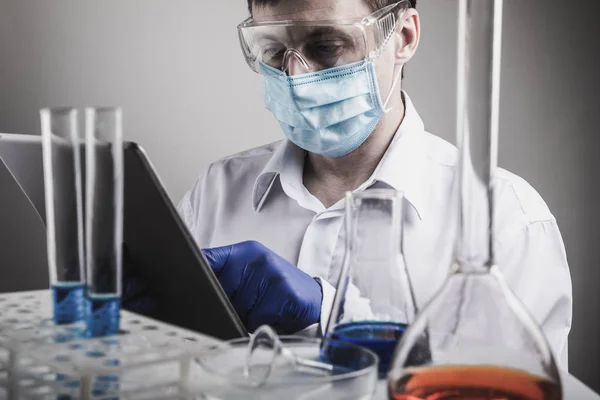 Científico profesional sosteniendo un tubo de ensayo y una tableta mientras realiza una investigación — Foto de Stock