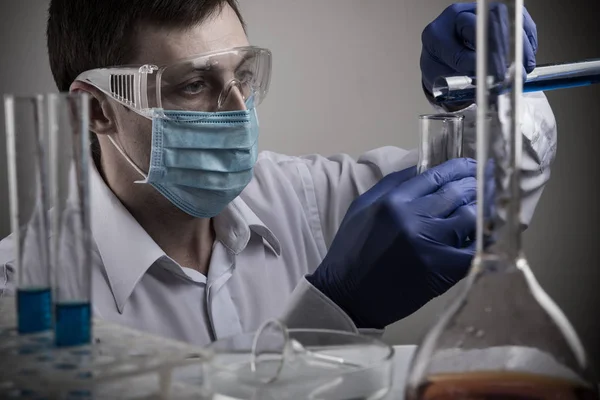 Científico profesional sosteniendo un tubo de ensayo y una tableta mientras realiza una investigación — Foto de Stock