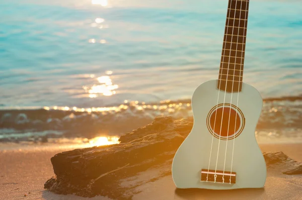 Gitar ukulele ile kum plajı üzerinde temiz su ve mavi gökyüzü. Seyahat ve yaşam tarzı kavramı.