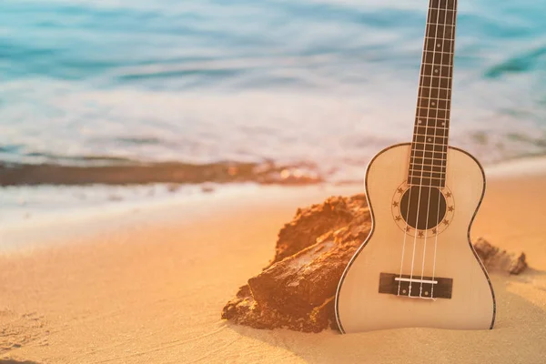 Gitar ukulele ile kum plajı üzerinde temiz su ve mavi gökyüzü. Seyahat ve yaşam tarzı kavramı.