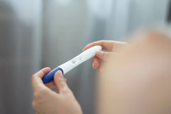 stock image Young woman with pregnancy test in hands Positive result