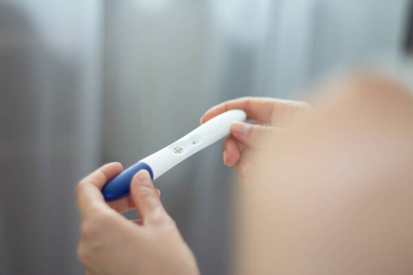Young woman with pregnancy test in hands Positive result