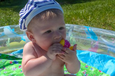 Çocuğun diş kesilir. İlk dişler kesilir, yeşil çim arka planı