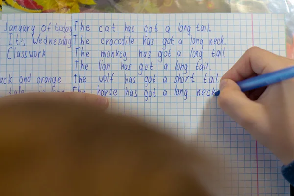 Domácí vzdělávání. Domácí práce po škole. Chlapec s perem psát test z angličtiny ručně na tradiční bílý Poznámkový blok papíru. — Stock fotografie