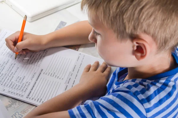 Educação doméstica. Trabalho em casa depois da escola. Menino com caneta escrita Inglês teste à mão em papel notepad branco tradicional . — Fotografia de Stock