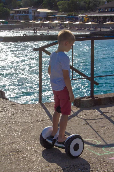 Boy riding an electric skateboard by the sea. Young man riding on the Hoverboard
