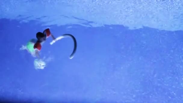 Niño nada en la piscina con mangas en la noche — Vídeos de Stock