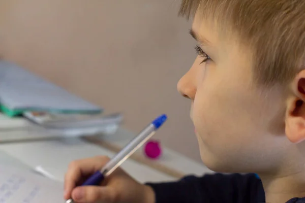전통적인 흰색 메모장 종이에 손으로 영어 단어를 쓰는 연필로 소년의 손을 클로즈업. 소년은 영어로 첫 편지를 씁니다. 자식 쓰기 — 스톡 사진