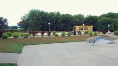 Genç bir adam atlar ve bir kaykay parkbir scooter üzerinde hileler yapar