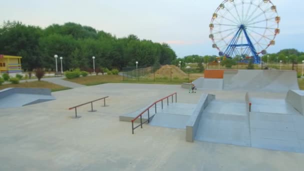 Un joven salta y hace trucos en una scooter en un skatepark — Vídeos de Stock