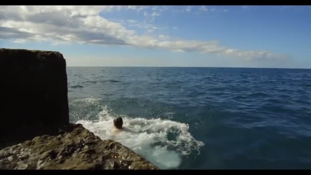 Glada barn hoppar i havet. Sakta i backarna. Glad liten pojke hoppar i vattnet nära havet. Grabben höjer stänk. — Stockvideo