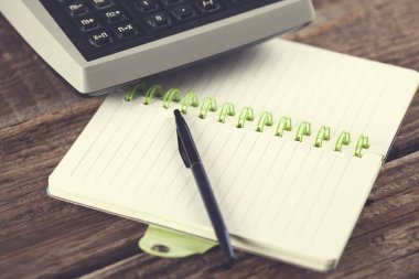 Masada kalem ve hesap makinesi olan not defteri