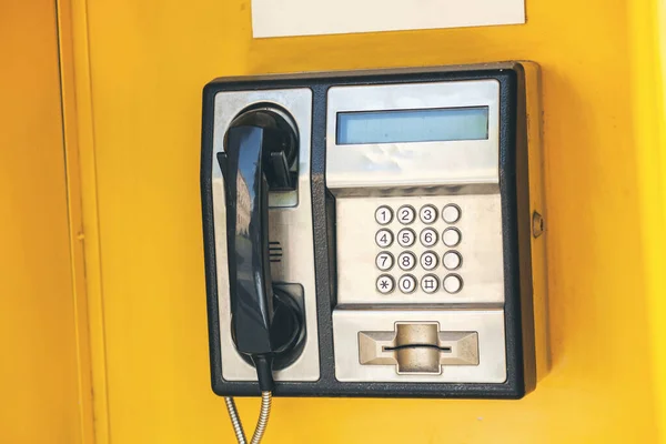 城市里一个黄色背景的公共付费电话的特写 图库图片