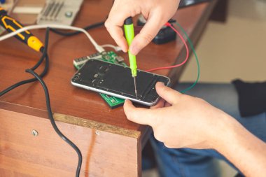 Tahta masadaki akıllı telefonu tamir ediyorum.